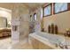 Elegant bathroom featuring a travertine-tiled shower, soaking tub, and vanity with ample natural light at 2430 S Geronimo Head Trl, Gold Canyon, AZ 85118