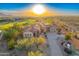 Stunning sunset aerial view of a luxury home with red tile roof and lush desert landscaping at 2430 S Geronimo Head Trl, Gold Canyon, AZ 85118