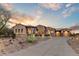 Desert home with stone accents, multiple garages, and a circular driveway under a vibrant sunset sky at 2430 S Geronimo Head Trl, Gold Canyon, AZ 85118