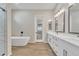 Bright bathroom featuring double sinks, soaking tub, and wood-look tile at 2458 E Lark St, Gilbert, AZ 85297