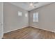 This bedroom features wood-look tile floors, a ceiling fan, and a view out to the yard through shuttered windows at 2458 E Lark St, Gilbert, AZ 85297