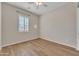 This bedroom has wood-look tile floors, neutral paint, a ceiling fan, and a view to the neighborhood through a shuttered window at 2458 E Lark St, Gilbert, AZ 85297