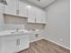 The laundry room provides upper cabinets, sink, white shaker cabinets, and tile flooring at 2458 E Lark St, Gilbert, AZ 85297