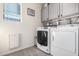 Well-equipped laundry room with modern washer, dryer, and overhead cabinets for storage at 2478 W Allens Peak Dr, San Tan Valley, AZ 85144