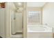 Well-lit bathroom with shower, soaking tub, and a decorative glass block window at 2755 E Cowboy Cove Trl, San Tan Valley, AZ 85143