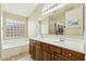 Bright bathroom with dual sinks, wood cabinetry, soaking tub, and natural light at 2755 E Cowboy Cove Trl, San Tan Valley, AZ 85143