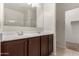 Bathroom featuring double sinks, dark wood cabinetry, a large mirror, and a view of the shower at 29065 N Fire Agate Rd, San Tan Valley, AZ 85143