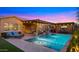 Backyard view of an in-ground pool, covered seating area, outdoor kitchen, and cozy place to relax after dark at 4462 S Frequency Dr, Mesa, AZ 85212