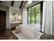 Luxurious bathroom featuring a marble soaking tub, large window, and elegant lighting at 6001 N 37Th Pl, Paradise Valley, AZ 85253