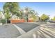 Street view showcasing the building behind a secure, bright orange gate with mature trees at 7047 E Earll Dr # 1002, Scottsdale, AZ 85251