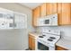 Cozy kitchen with white oven/microwave and light wood cabinets; bright window at 920 N 82Nd N St # H203, Scottsdale, AZ 85257