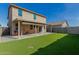 View of backyard with a covered patio, artificial grass, and a two-story house at 11509 W Boca Raton Rd, El Mirage, AZ 85335