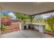 A covered back patio features a stone brick outdoor kitchen area and a view of the backyard at 14608 N Montego Ct, Phoenix, AZ 85053