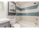This bathroom has a gray vanity with drawers, a toilet, a tub, and striped tile at 14608 N Montego Ct, Phoenix, AZ 85053