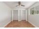 Bright bedroom featuring hardwood floors, a ceiling fan, a window, and closet space at 14608 N Montego Ct, Phoenix, AZ 85053