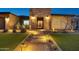 A stunning nighttime view of a single-story home showcases a beautifully illuminated yard and stone entryway at 1464 E Aris Dr, Gilbert, AZ 85298