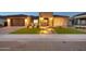 A well-lit home features a charming stone entry, desert landscaping, and a paved driveway at 1464 E Aris Dr, Gilbert, AZ 85298