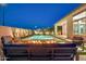Outdoor oasis with fire pit, cacti, and inviting pool at night at 1464 E Aris Dr, Gilbert, AZ 85298
