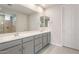 Bathroom featuring double sinks with sleek gray vanities, large mirrors, and a view of the shower at 17614 W Rancho Dr, Litchfield Park, AZ 85340