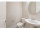A clean powder room featuring a pedestal sink, round mirror, and a toilet at 17614 W Rancho Dr, Litchfield Park, AZ 85340