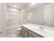 A well-lit bathroom with a shower-tub combo, modern vanity, and gray cabinets at 17614 W Rancho Dr, Litchfield Park, AZ 85340