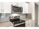 Close-up of oven and microwave with modern finishes and gray backsplash at 17851 W Getty Dr, Goodyear, AZ 85338