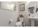 Clean and simple powder room with a pedestal sink, round mirror, and neutral decor at 19703 W Badgett Ln, Litchfield Park, AZ 85340