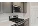 Close-up of the kitchen's stainless steel stove and microwave with a white countertop and gray cabinets at 2681 N Riverside Dr, Florence, AZ 85132