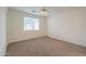 Bright bedroom featuring neutral carpet, a ceiling fan, and a large window for natural light at 325 W Seaside Dr, Casa Grande, AZ 85122