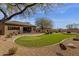 Expansive backyard featuring a putting green, brick patio, desert landscaping, and mature trees at 33250 N 71St St, Scottsdale, AZ 85266