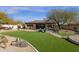 Beautiful backyard with manicured lawn, putting green, brick patio and desert landscaping at 33250 N 71St St, Scottsdale, AZ 85266