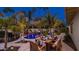 An outdoor dining setup alongside a pool is enhanced by lush landscaping and mature palm trees at 4114 E Desert Cove Ave, Phoenix, AZ 85028