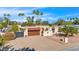 Charming exterior featuring a terra cotta roof, a large driveway, and a backdrop of mature palm trees at 4114 E Desert Cove Ave, Phoenix, AZ 85028