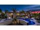 An inviting pool with stone landscaping and illuminated palm trees enhances this outdoor living space at dusk at 4114 E Desert Cove Ave, Phoenix, AZ 85028
