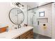 Modern bathroom with a subway tile shower, glass door, dark fixtures, and a wood vanity with a round mirror at 5045 E Calle Del Sol --, Cave Creek, AZ 85331