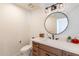 Powder room with round mirror and wood vanity with stone countertop at 5045 E Calle Del Sol --, Cave Creek, AZ 85331
