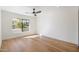 Minimalist bedroom with hardwood floors, a large window offering street views, and a ceiling fan at 7553 E Woodshire Cv, Scottsdale, AZ 85258