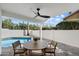 Covered patio with outdoor dining, ceiling fan, and serene pool views at 7553 E Woodshire Cv, Scottsdale, AZ 85258