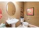 Stylish powder room with a pedestal sink, round mirror, decorative wallpaper, and classic fixtures at 7654 W Congressional Way, Florence, AZ 85132