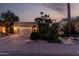 Inviting single-Gathering home featuring a two-car garage, tropical landscaping, and warm exterior lighting at twilight at 8737 E San Vicente Dr, Scottsdale, AZ 85258