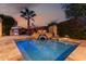 Beautiful pool with stone surround, waterfall feature and lush landscaping at dusk at 8737 E San Vicente Dr, Scottsdale, AZ 85258