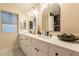 Modern bathroom featuring a dual sink vanity with quartz countertops and arched mirrors and dark tiled shower in the background at 10018 N 103Rd Ave, Sun City, AZ 85351