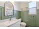 Stylish bathroom featuring green wainscoting, a framed mirror, neutral vanity with a white sink and a shower-over-tub at 1232 E Silver Reef Dr, Casa Grande, AZ 85122