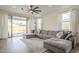 Bright living room with a large gray sectional, wood floors, and sliding glass doors leading to the backyard at 1232 E Silver Reef Dr, Casa Grande, AZ 85122