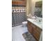 Modern bathroom featuring a wooden vanity, patterned shower curtain, and tile flooring at 13034 W Peach Blossom Dr, Sun City West, AZ 85375