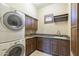 Practical laundry room with granite counters, sink, cabinets, and washer/dryer for seamless chores at 15135 E Monument Rd, Scottsdale, AZ 85262