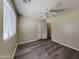 A bedroom featuring a ceiling fan, window and door to the room, with wood-look flooring at 17914 N Fiano Dr, Maricopa, AZ 85138