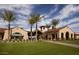 View of community clubhouse with manicured lawns, palm trees and arched entryways at 18742 N 269Th Ln, Buckeye, AZ 85396