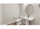 Elegant powder room with pedestal sink, decorative mirror, and modern fixtures at 18742 N 269Th Ln, Buckeye, AZ 85396