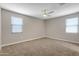 Spacious bedroom with two windows, plush carpet, and a ceiling fan at 24220 W Ripple Rd, Buckeye, AZ 85326